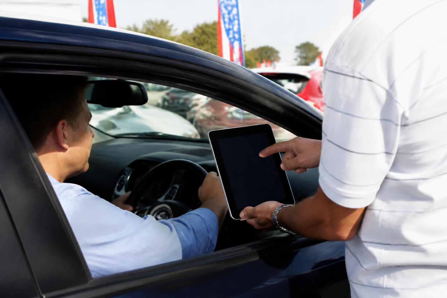 A buyer reviewing auto loan terms during a test drive on a car lot.