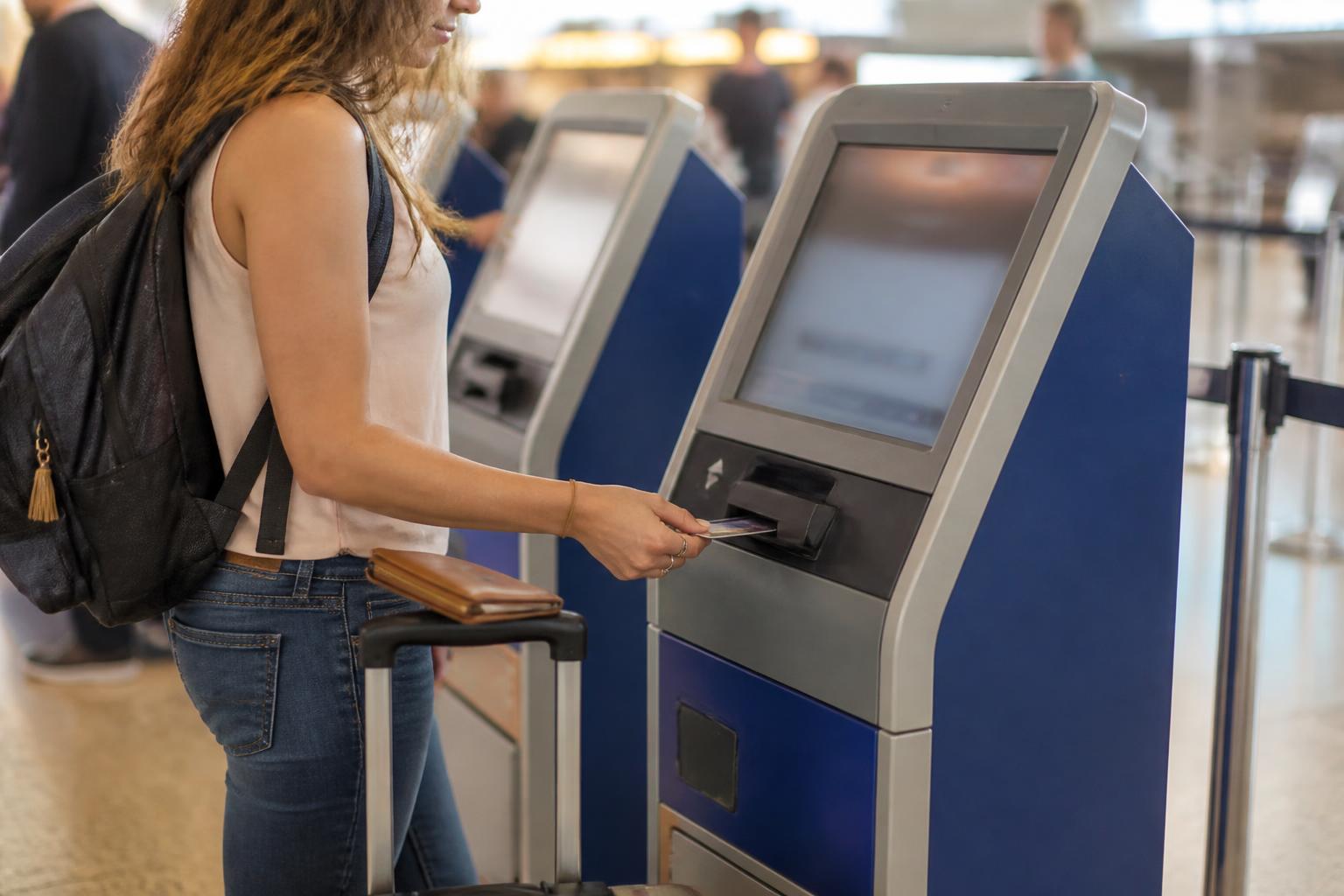 A traveler paying at an airport kiosk with a generic card.