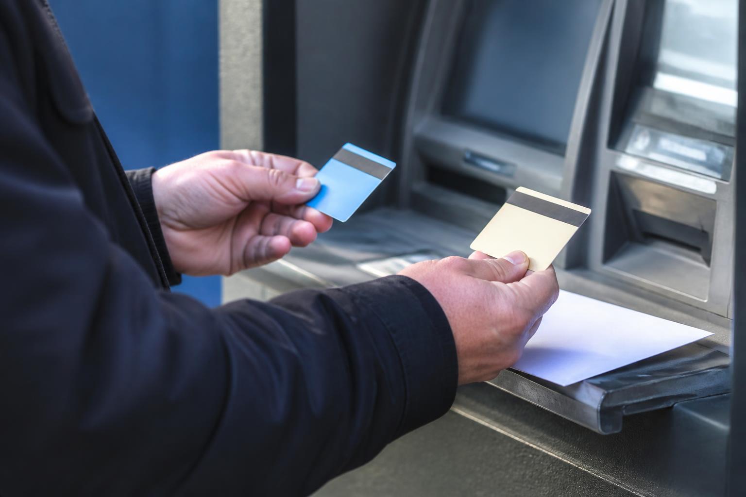 A person comparing a deposit option and prepaid-style card at an ATM.