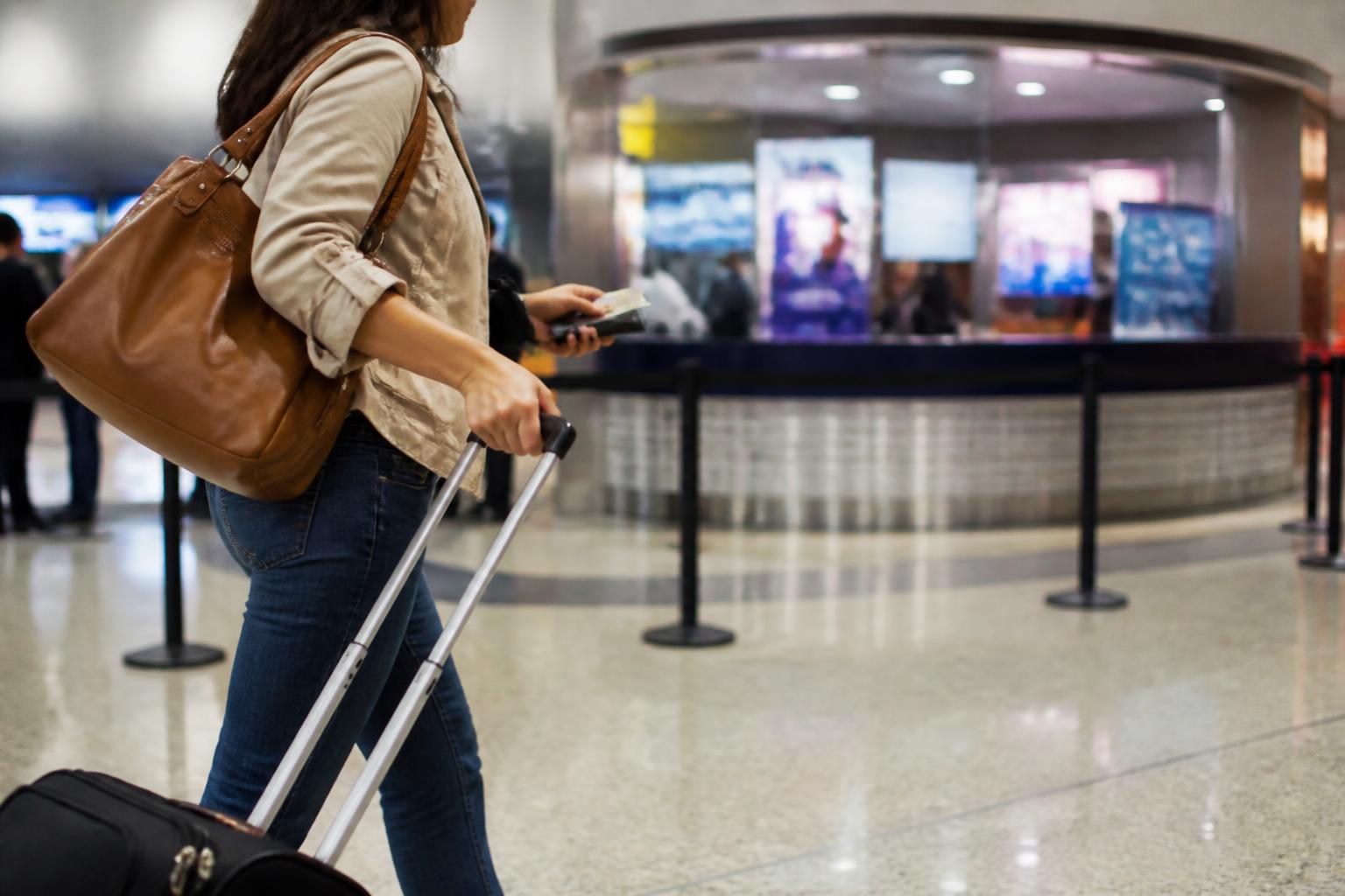 A traveler checking a generic card near a blurred airport currency counter.