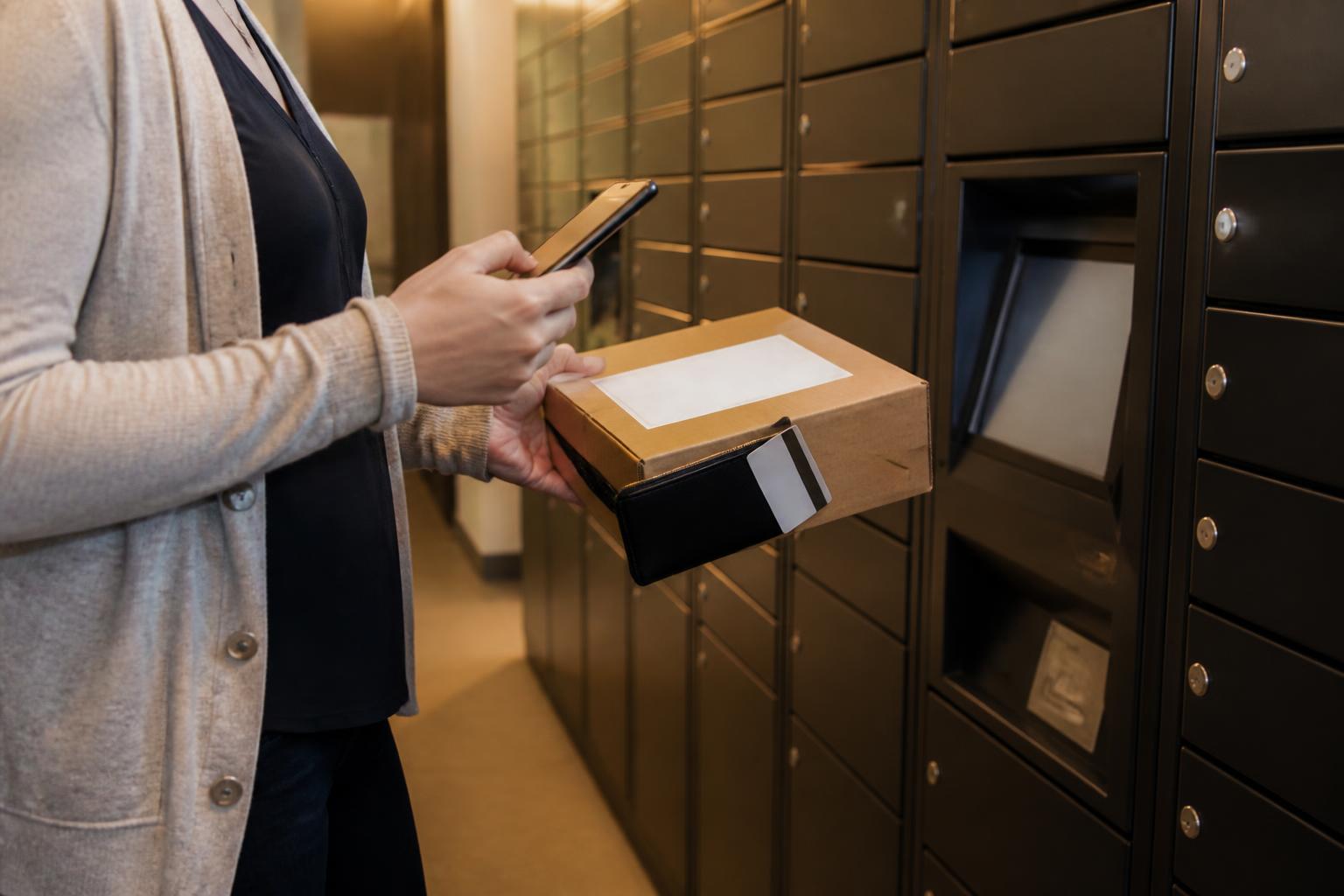 A resident checking an unbranded package near apartment package lockers.