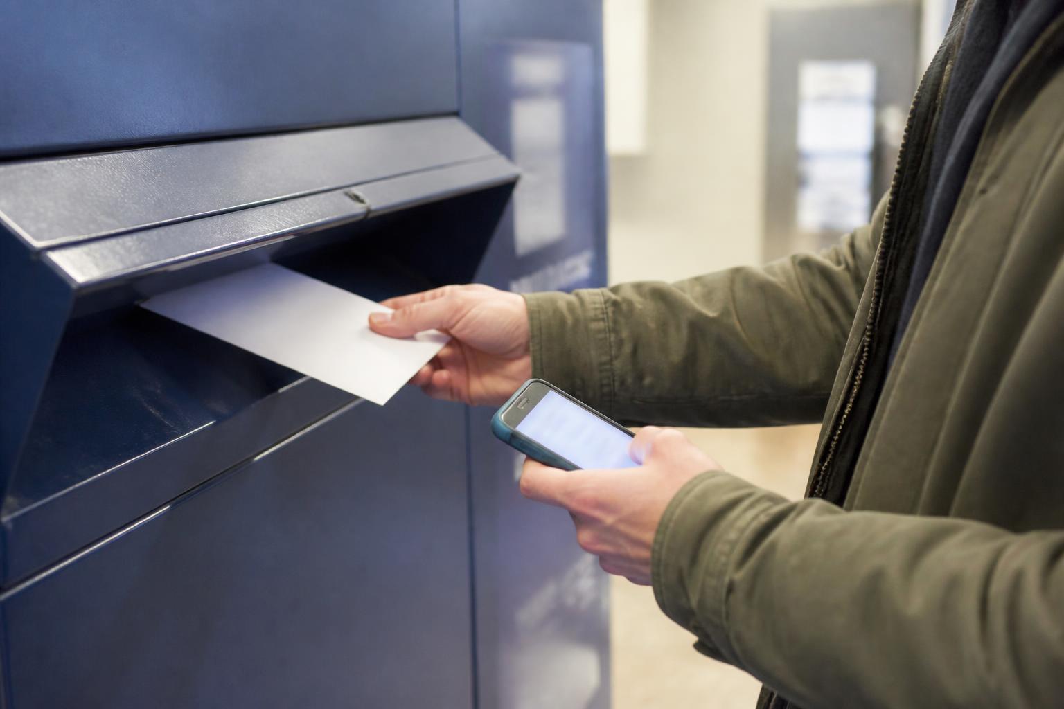 A taxpayer mailing a payment envelope at the post office.