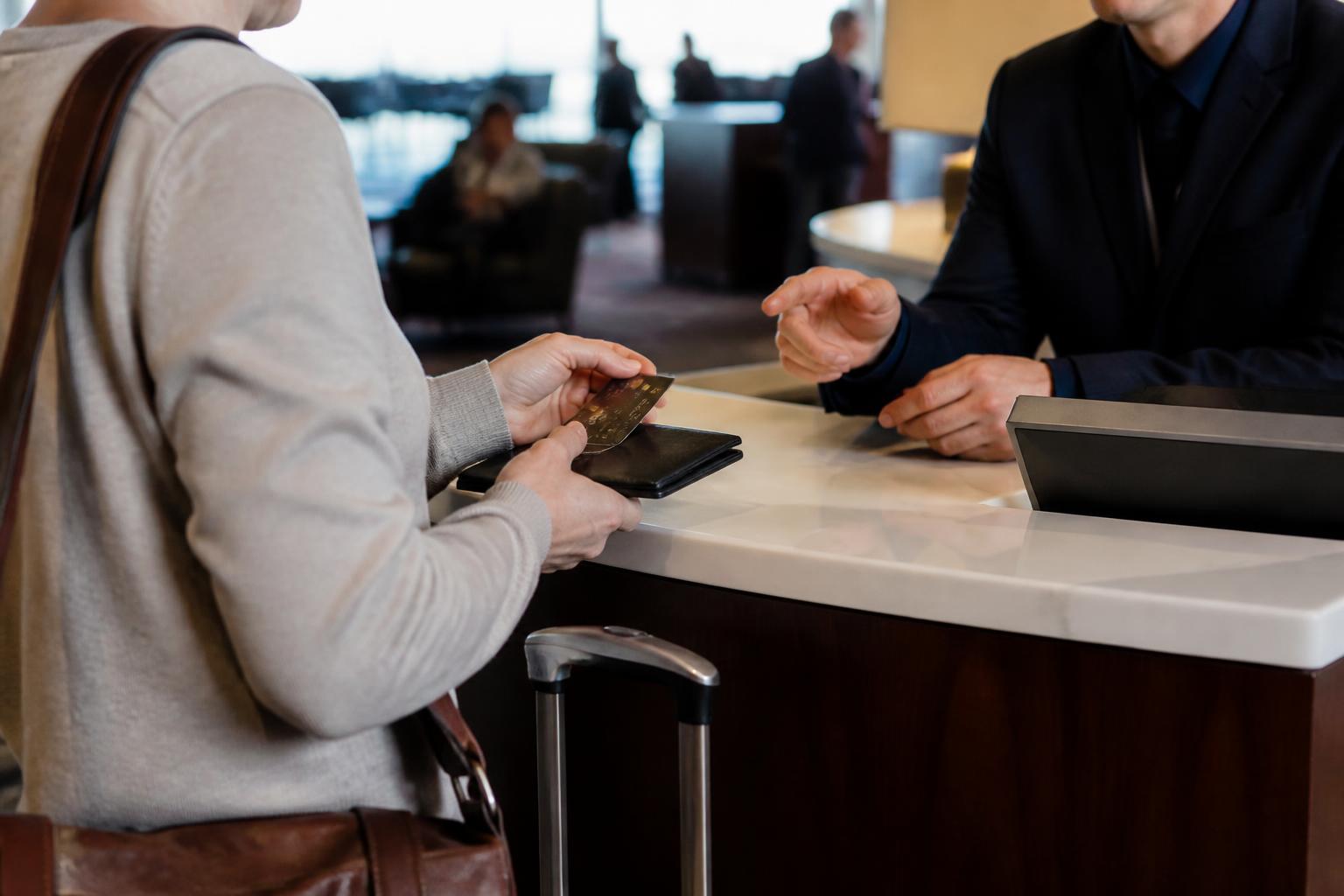 A traveler asking about card benefits at an airport service desk.