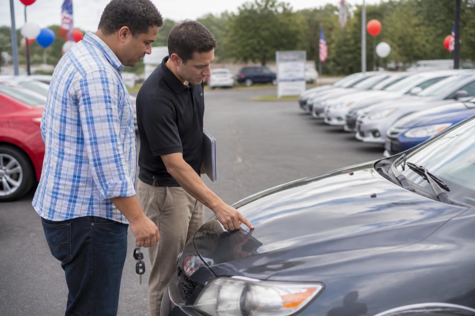 A buyer and salesperson inspecting a trade-in car before Labor Day.