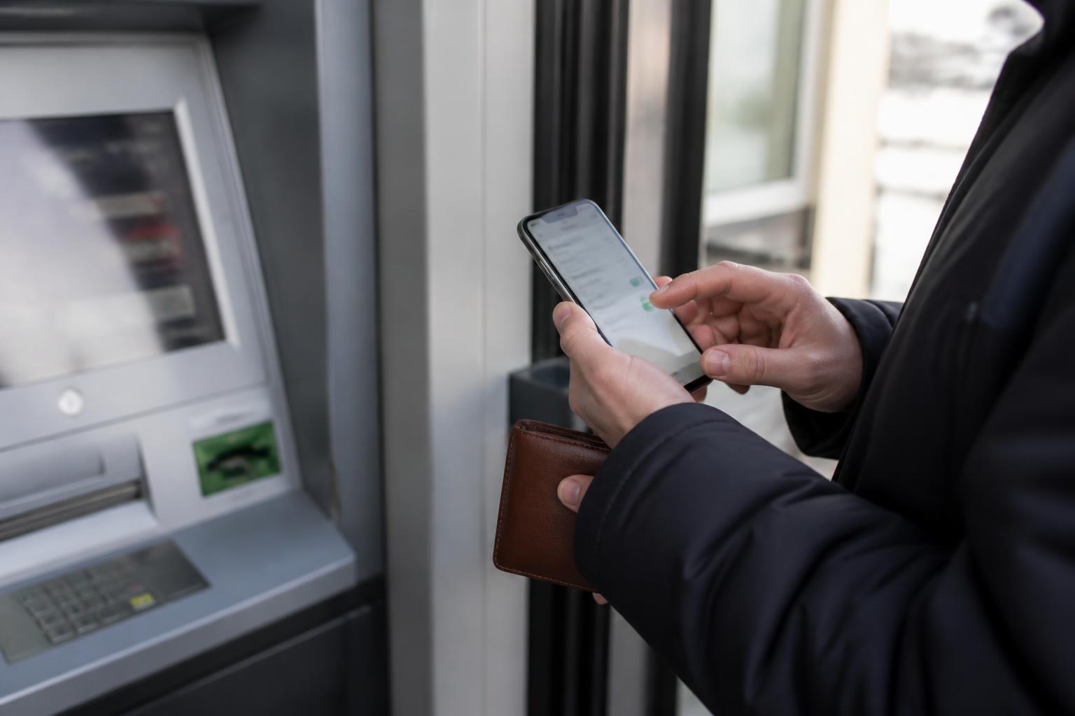 A customer setting up an account alert in a bank ATM vestibule.
