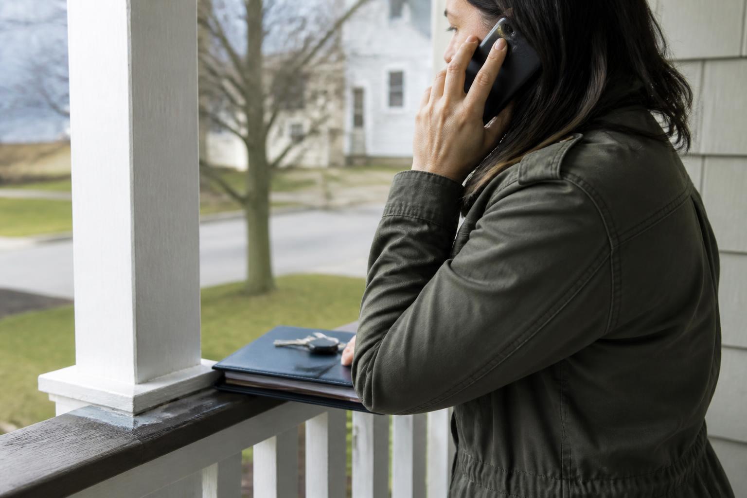 A homeowner calling a mortgage servicer from the front porch.