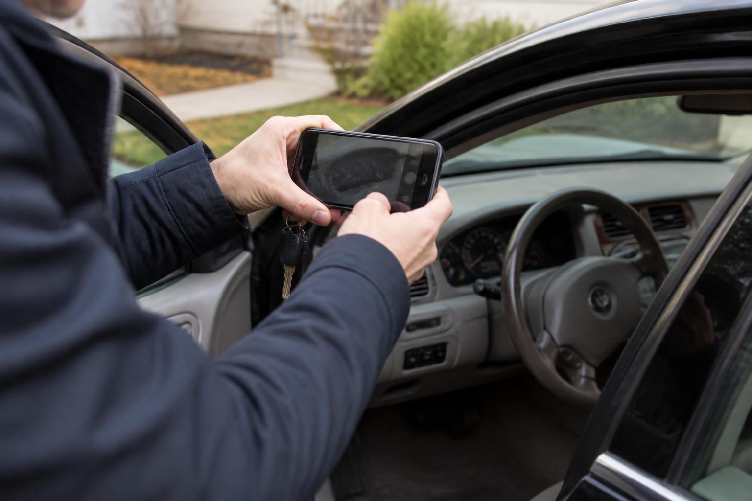 A driver photographing mileage through an open car door.